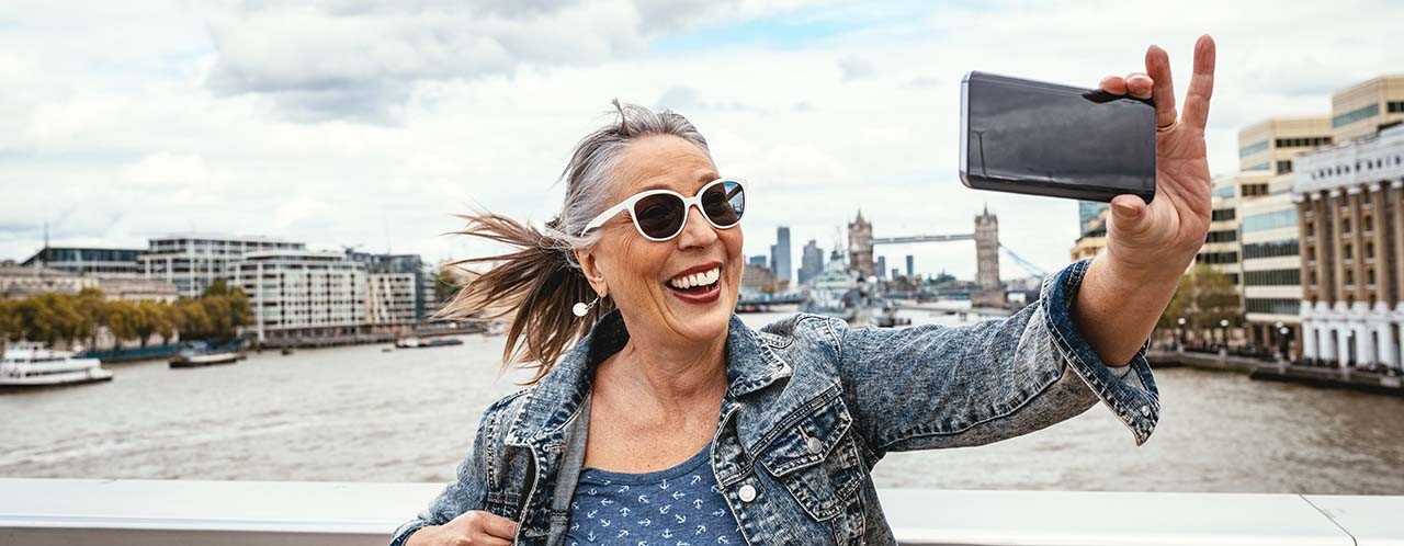 Woman taking a selfie on a bridge over the River Thames in London.
