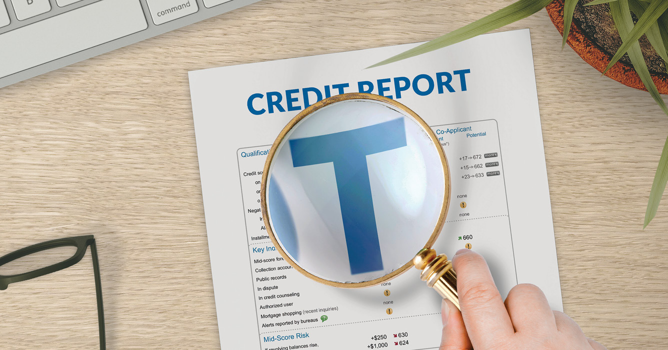 Magnifying glass highlighting a blue T in a credit report.