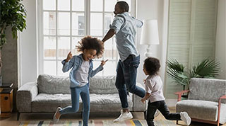 Father and his daughters dancing in living room.