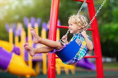 Young boy swinging at playground.