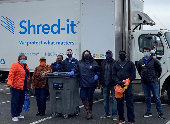 Employees standing beside ShredIt truck.