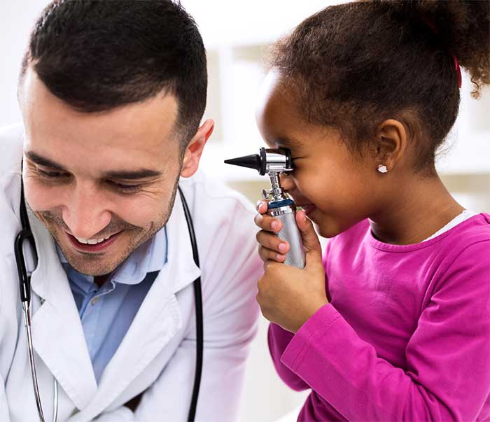 Young girl using otoscope to look in doctor's ear.