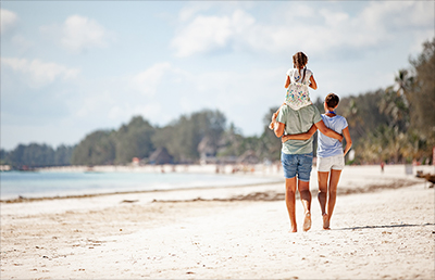 Parents and child walking on beach.