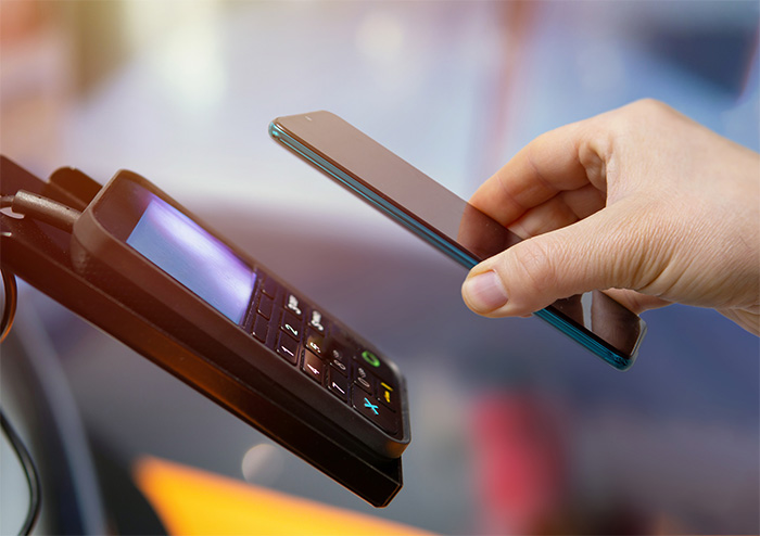Hand holding a smartphone in front of a card reader.