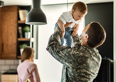 Military man holding his child in the air.