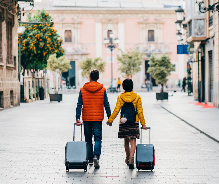 Couple walking in foreign city with suitcases