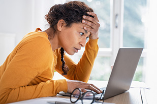 woman looking at her laptop in distraught