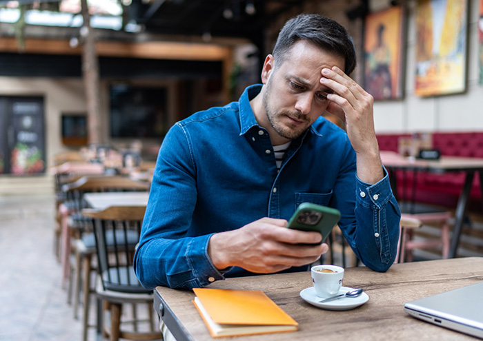 man looking at his phone in distraught